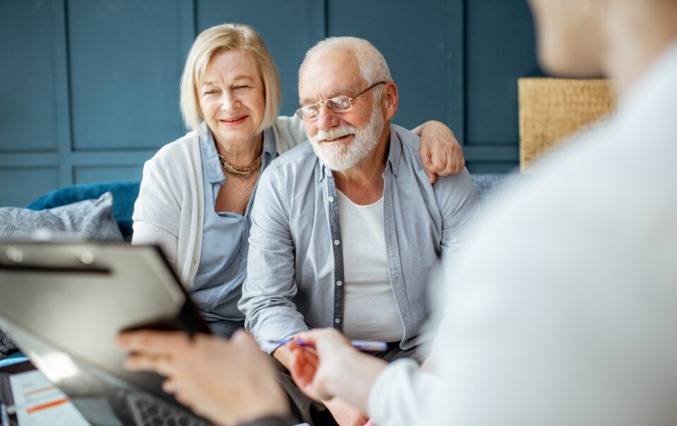 Senior couple consulting with a legal advisor in an office setting, discussing UK visa options and financial legal services.