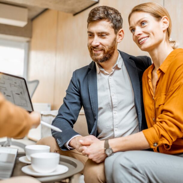 Young couple engaging with a real estate consultant, discussing property options over coffee, in a modern office setting.