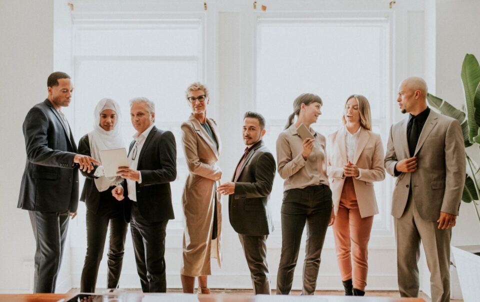Diverse business team in formal attire collaborating and discussing in a bright office setting, reflecting Abrahams Solicitors' focus on corporate legal services.