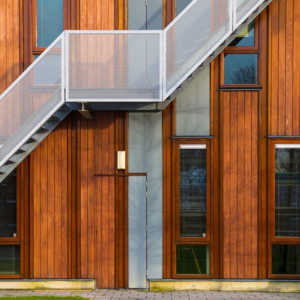 Modern wooden building exterior featuring a metal staircase and large windows, symbolizing contemporary architecture and design relevant to legal services and office spaces.
