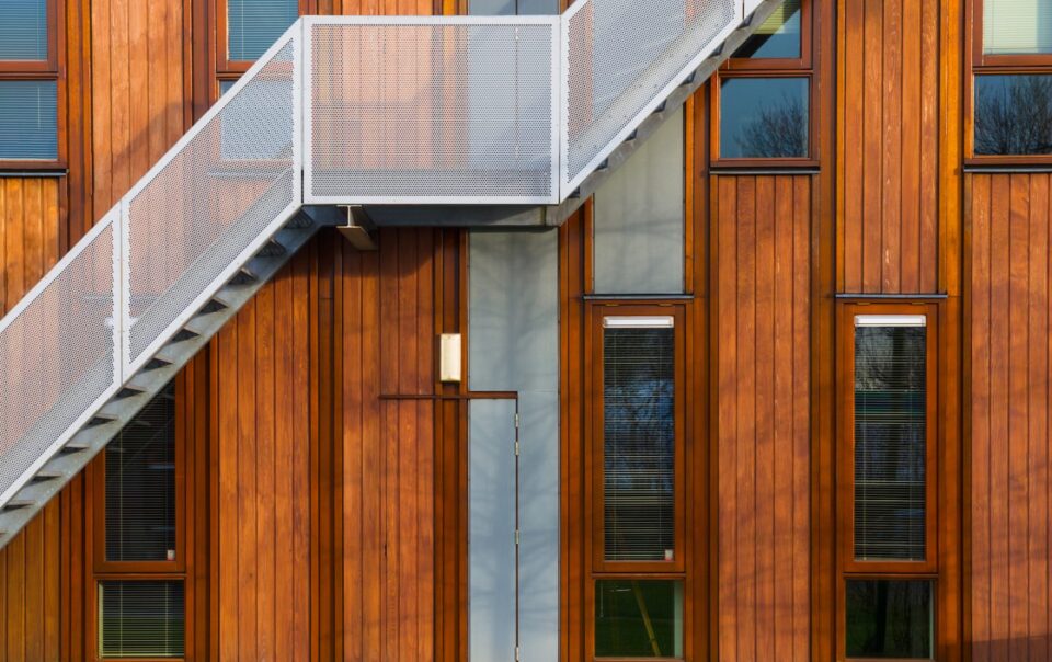 Modern wooden building exterior with metal staircase and large windows, reflecting architectural design relevant to legal office settings.