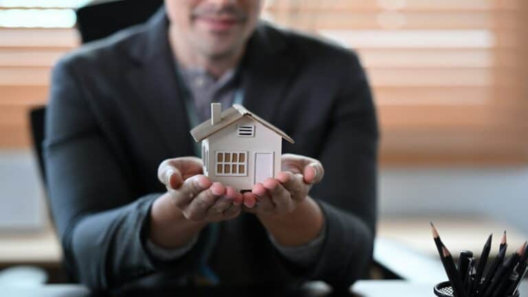 Man holding a small house model, representing real estate investment and tenant rights in housing disrepair claims.